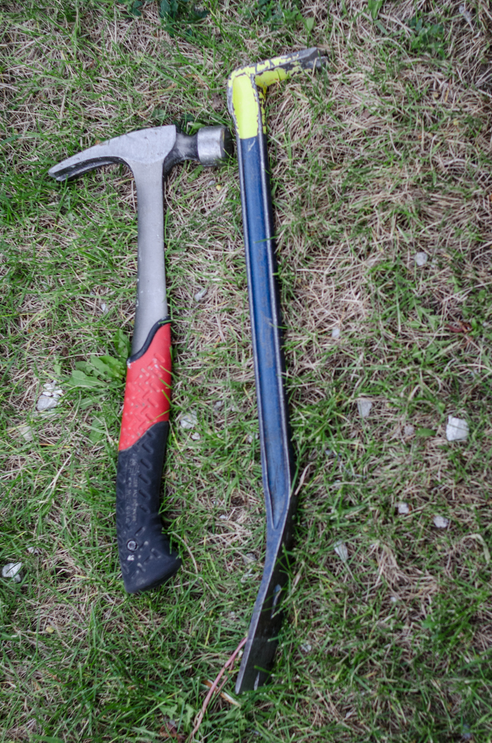hammer and pry bar in grass to use for taking apart a pallet