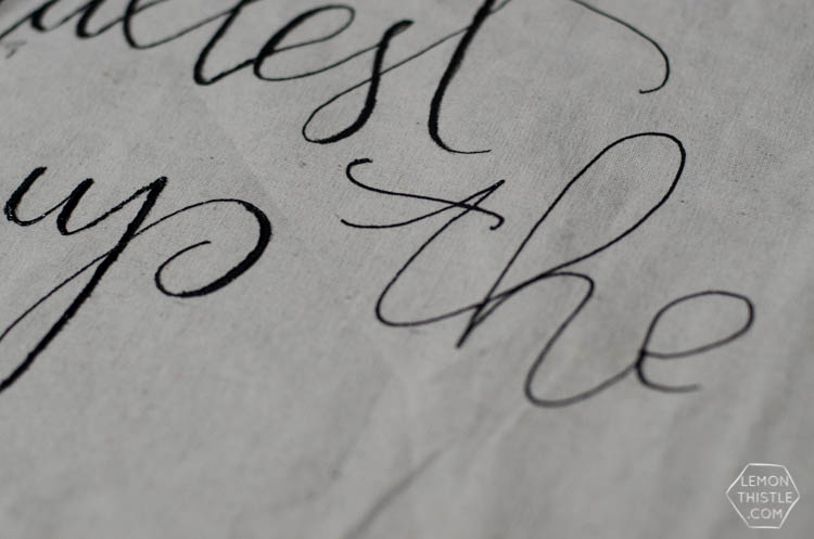 DIY giant wall hanging for simple baby shower decor- close up of half finished lettering on drop cloth