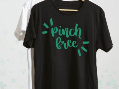 hand holding shirts on hangers, pinch free hand lettered design on shirt in green