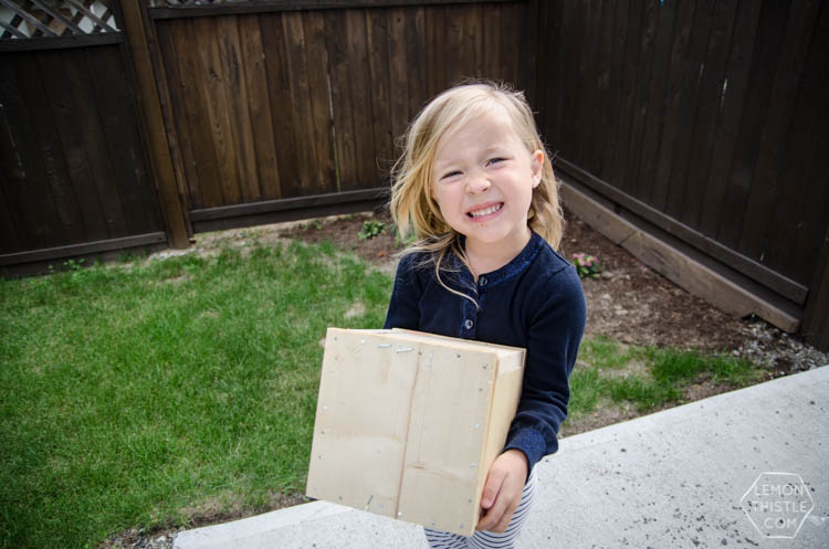 Girl holding wooden box nailed shut with gift card inside