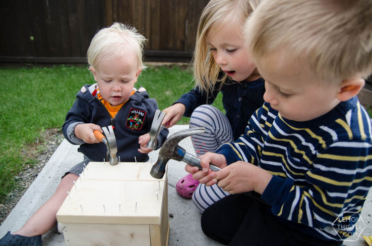 Kids hammering nails to close a wooden crate with gift card inside