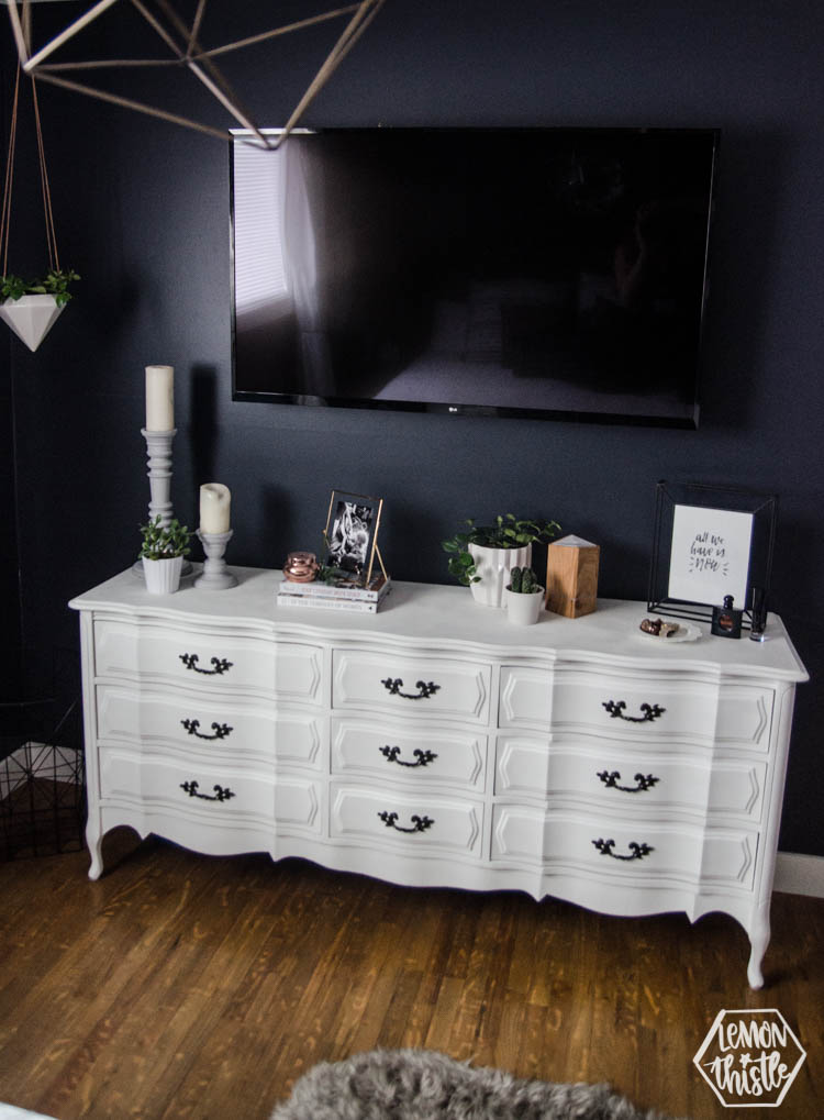 Vintage chalk paint white dresser with TV over in navy master bedroom