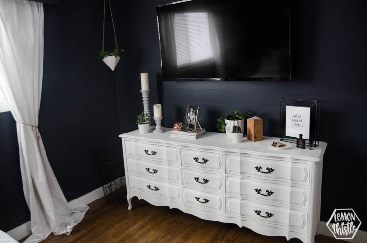 Vintage chalk paint white dresser with TV over in navy master bedroom