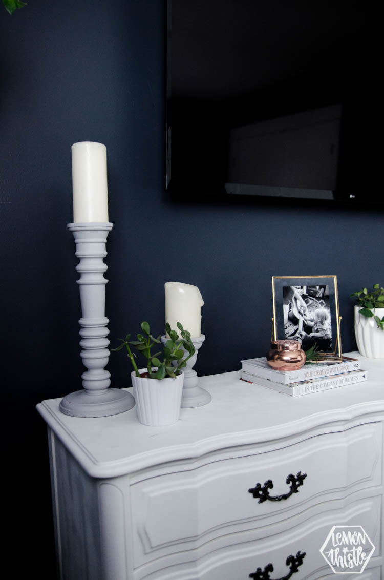 Tall candlesticks help frame the TV above the long dresser.