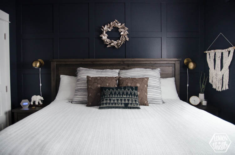 Navy Bedroom with walnut coloured wood headboard and gold sconces above nightstands