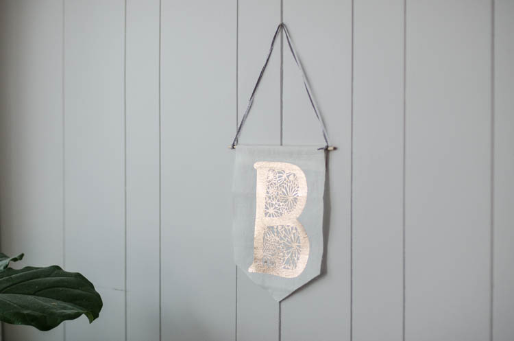 Rose gold iron on foil on a floral monogram pennant- from an angle to show it reflecting light- great shine!