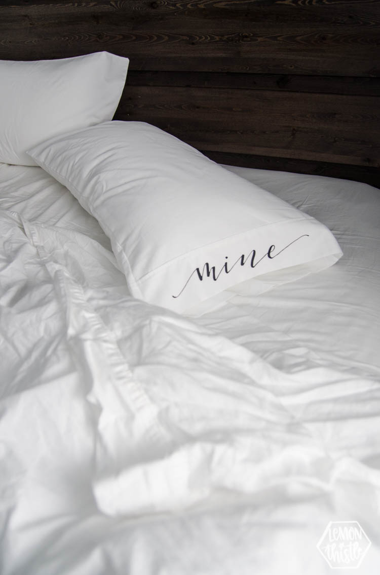 Unmade bed with white pillow case that has black lettering reading, 'mine' (DIY)