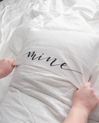 Putting on a king size pillow cover with the lettering 'mine'