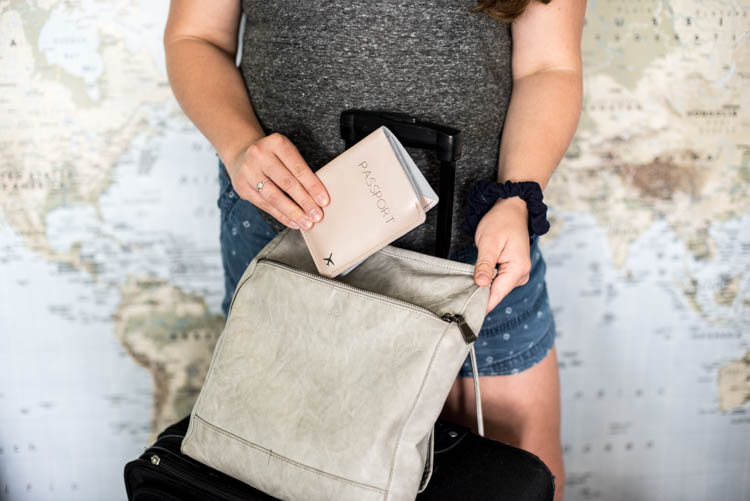 DIY leather passport holder being put in bag for travel