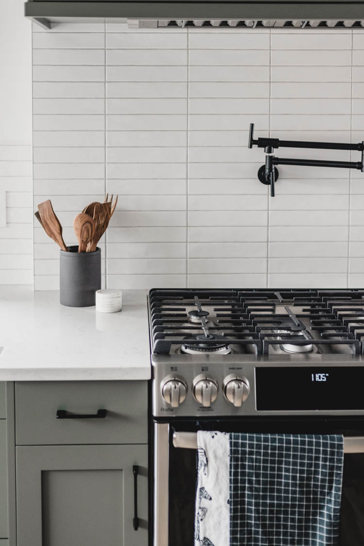 Modern black pot filler with green cabinets... so good!