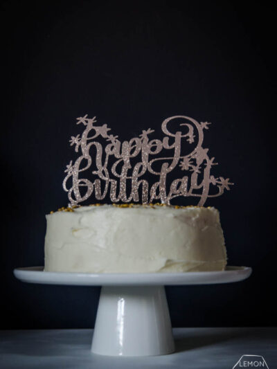 Happy Birthday glittery cake topper on white iced cake