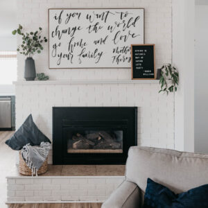 white brick fireplace decorated with black vases and white details, hand lettered art and letterboard reads 'spring is nature's way of saying let's party' - robin williams quote