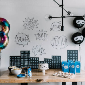 Tablescape with cartoon buildings and word bubbles for superhero birthday party