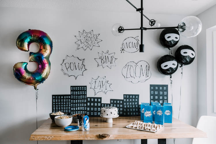 Tablescape with cartoon buildings and word bubbles for superhero birthday party