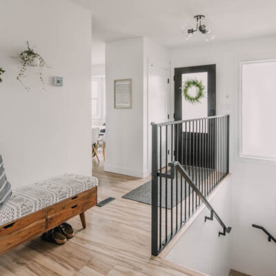 Bright white entry way makeover with black door and metal railing... plus that storage bench!