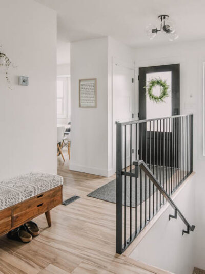 Bright white entry way makeover with black door and metal railing... plus that storage bench!