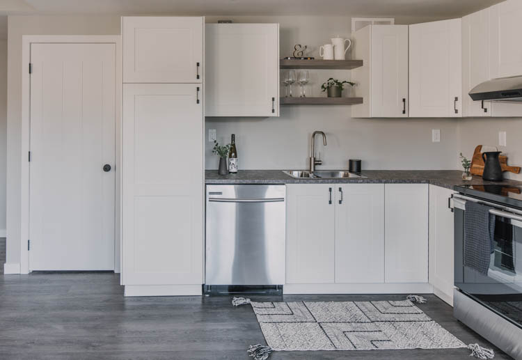 Modern basement kitchen with black hardware and white shaker cabinets