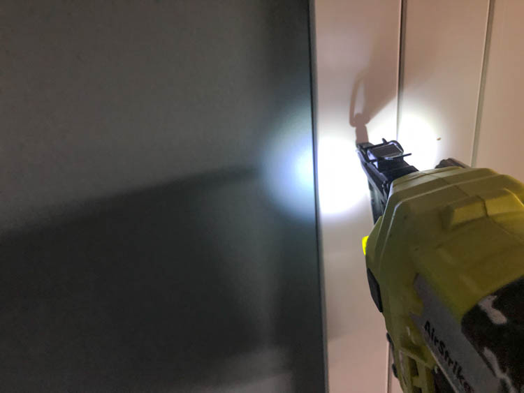 Using a brad nailer to affix baseboard to walls for a vertical shiplap look