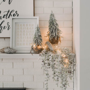 Modern holiday mantel decor... full of black, white, metallics, and frosted greenery