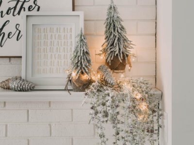 Modern holiday mantel decor... full of black, white, metallics, and frosted greenery