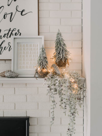 Modern holiday mantel decor... full of black, white, metallics, and frosted greenery