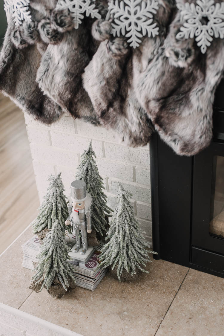 Nutcracker with frosted christmas trees on a holiday hearth