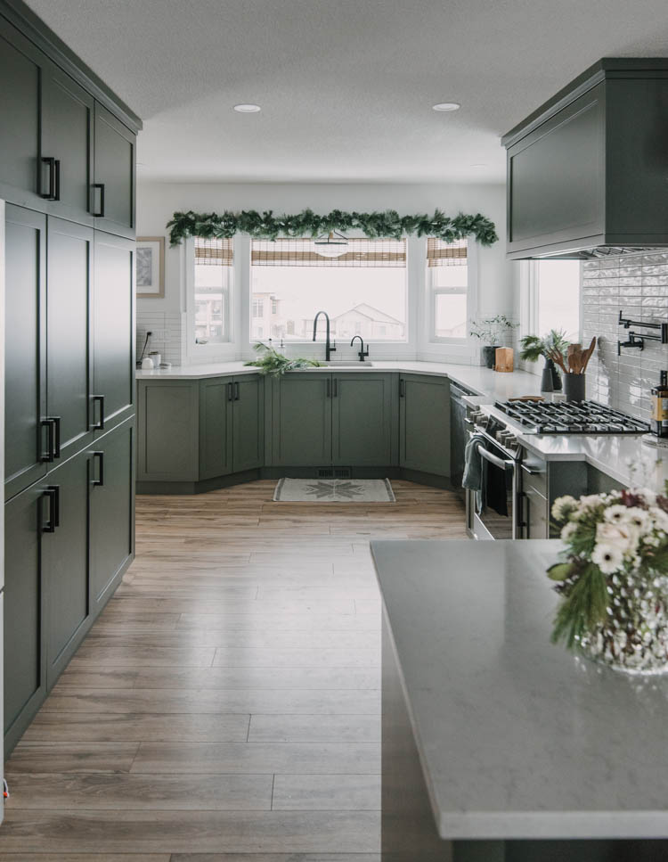 Green kitchen decorated for christmas- love the garland over the windows