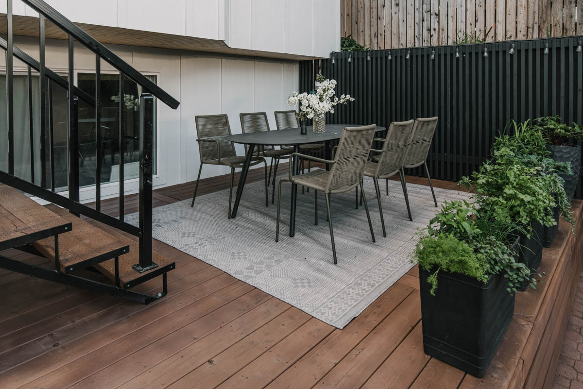 wooden deck with patterned grey rug and outdoor dining table