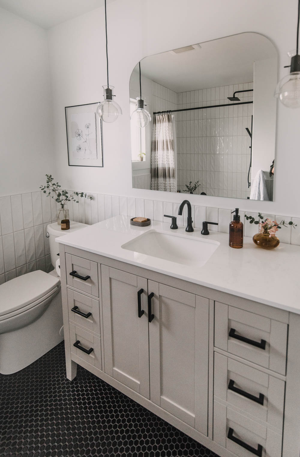 pendant lights with an arch mirror over the vanity