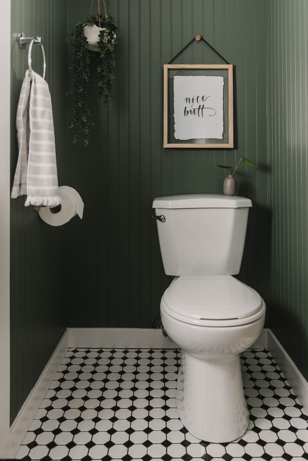 green bathroom with beadboard and black and white tiles.