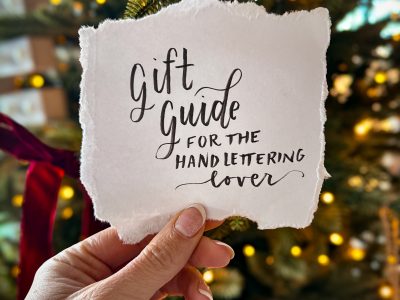 gift guide for the hand lettering lover, lettered on torn paper held in front of a christmas tree