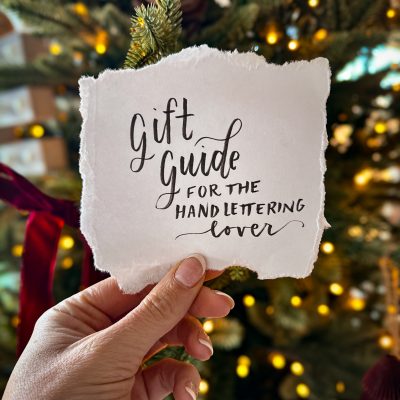 gift guide for the hand lettering lover, lettered on torn paper held in front of a christmas tree
