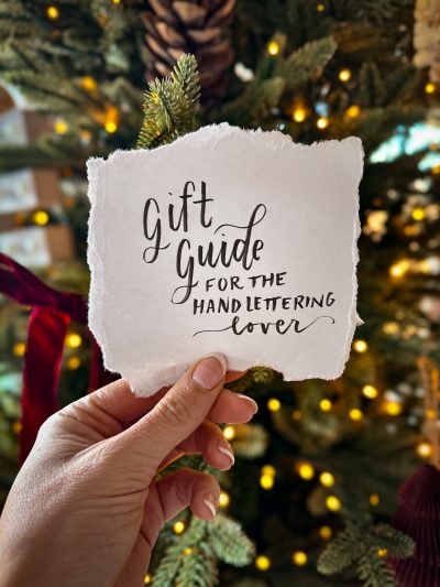 gift guide for the hand lettering lover, lettered on torn paper held in front of a christmas tree