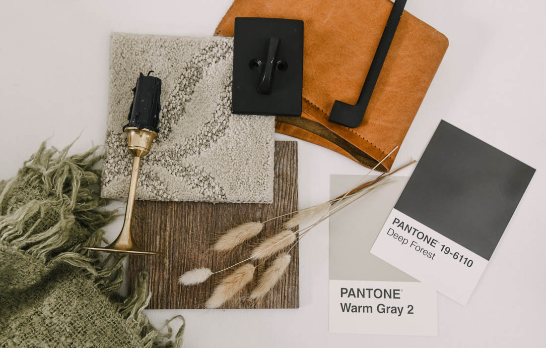 rustic leather, black hardware, and tan carpet with medium wood in a flatlay