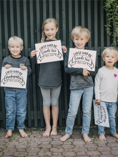 Children with back to school signs with the year and grade.