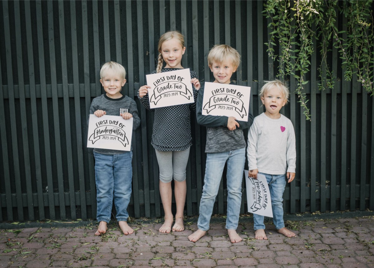 Children with back to school signs with the year and grade.