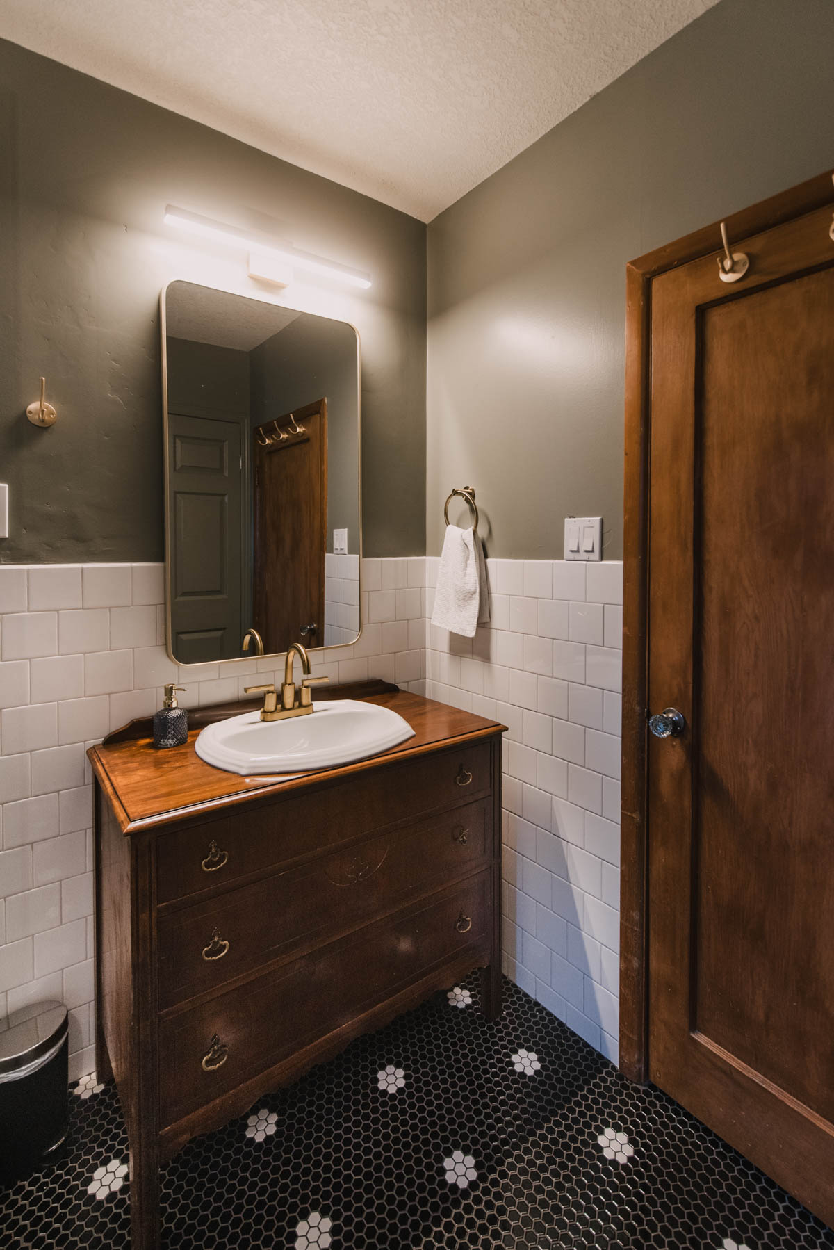 Classic Black and White tile in a green bathroom with wood vanity and trim