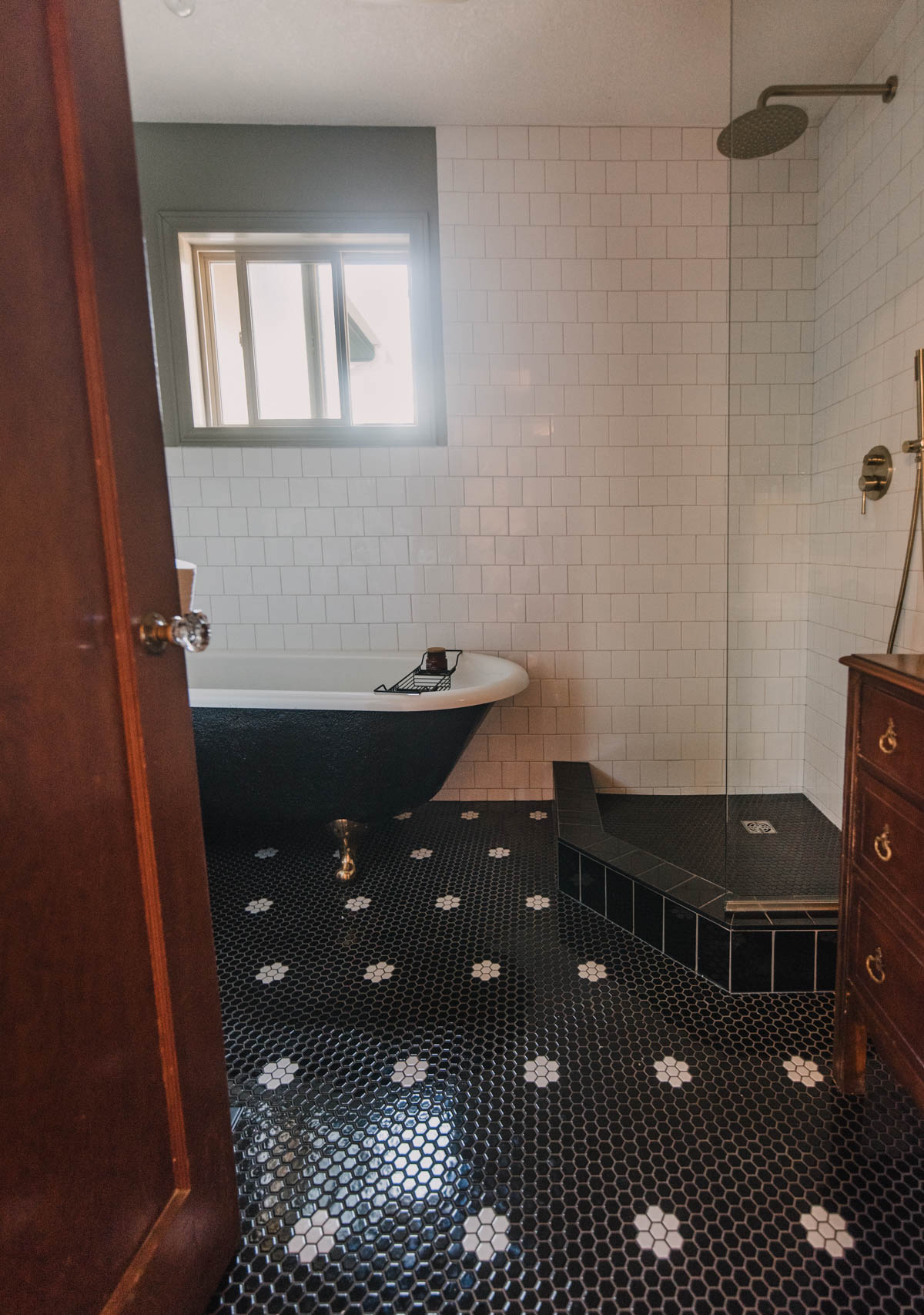 Classic bathroom renovation with clawfoot tub, wood vanity and black and white tile