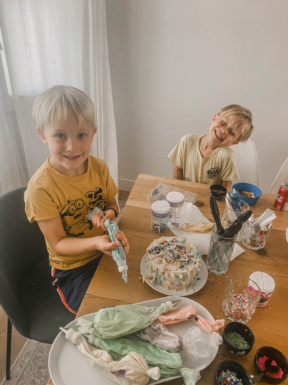 Boys decorating a cake piled high with icing at a cake decorating party