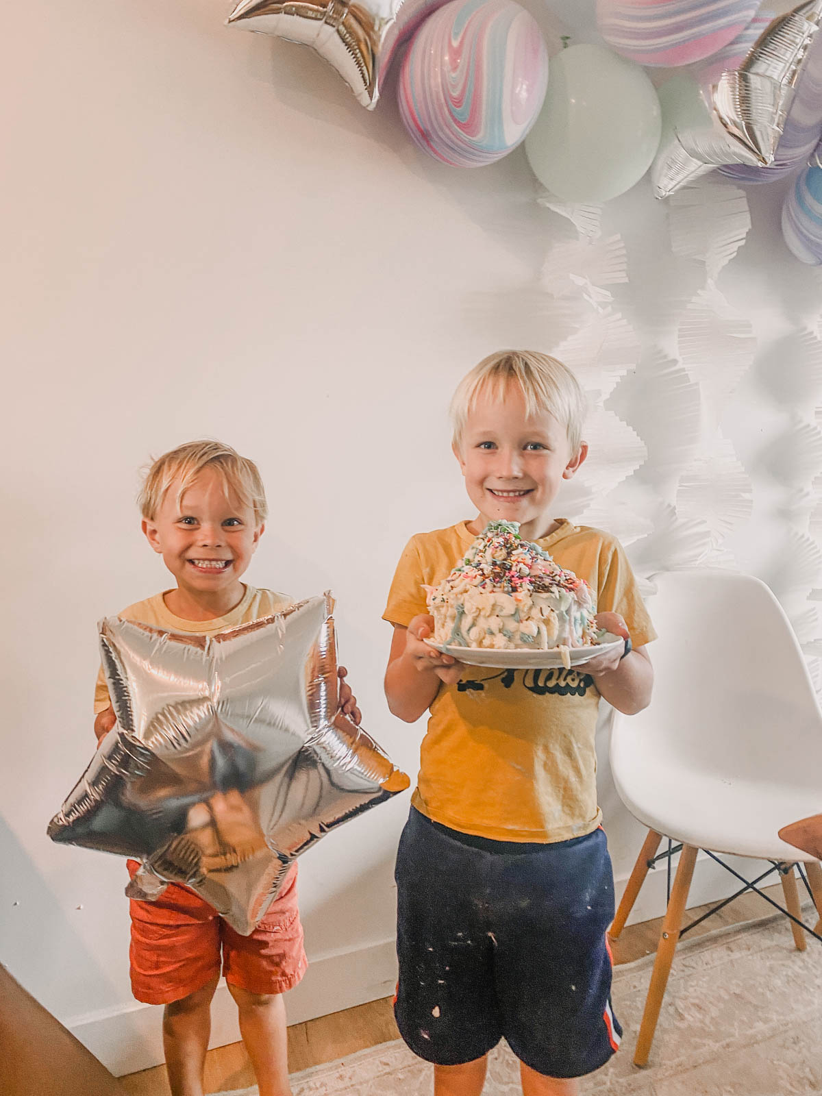 Boys holding cake they decorated, piled high with icing at a cake decorating party