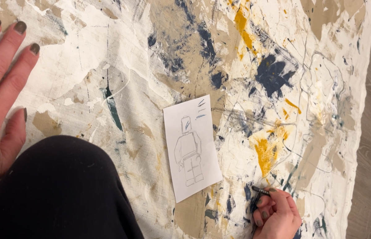 illustrating on a fabric wall flag with oil pastel- drawing a line art lego man