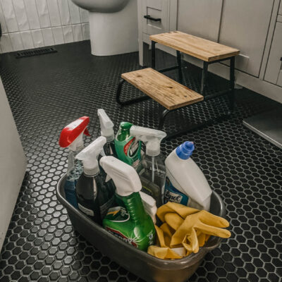 plastic caddy full of bathroom cleaning supplies on bathroom floor