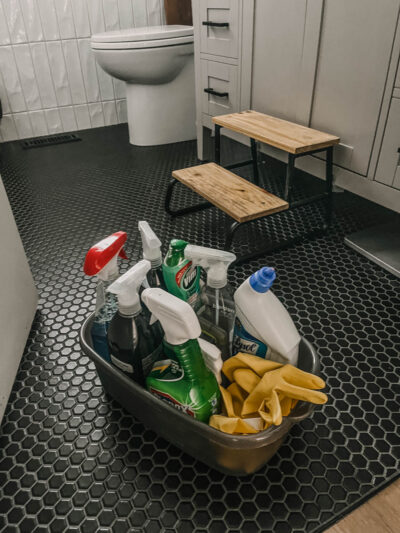 plastic caddy full of bathroom cleaning supplies on bathroom floor