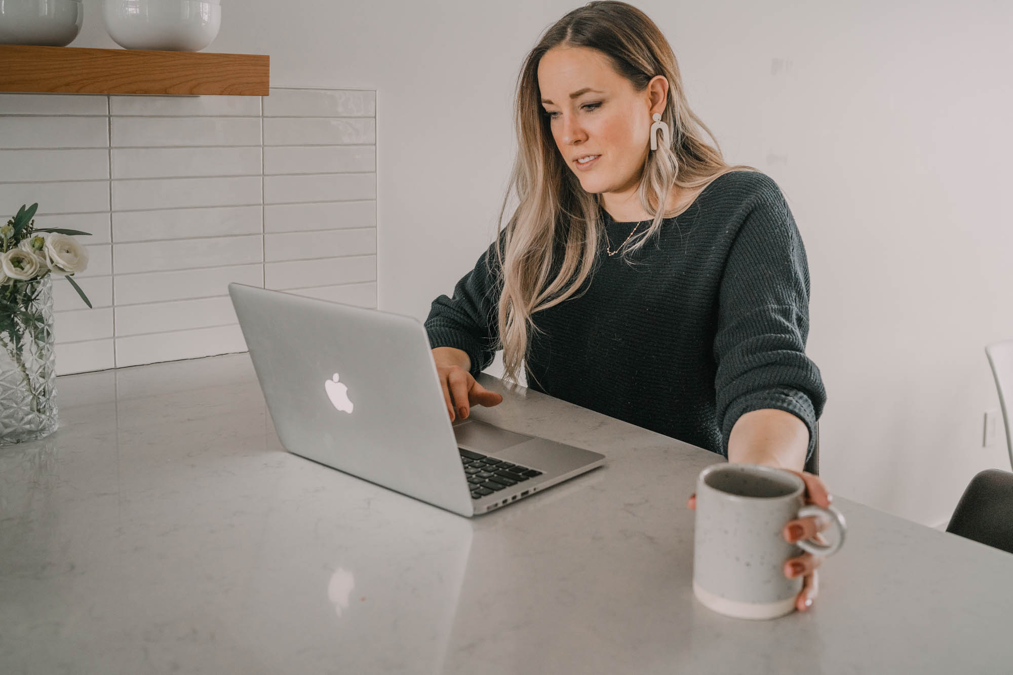 girl sitting at computer at kitchen counter with coffee