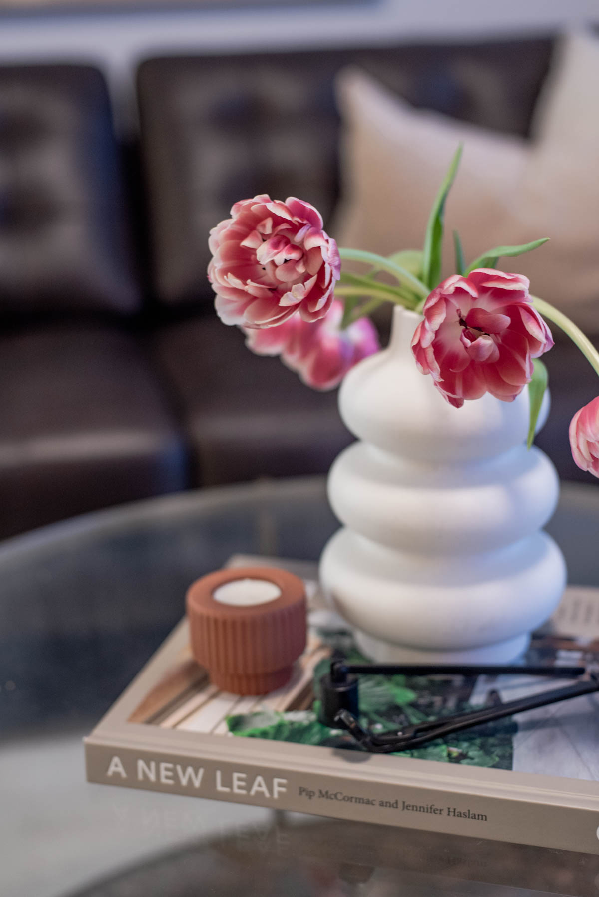 Simple spring decor ideas- vase with tulips beside springs scented candle on a coffee table book