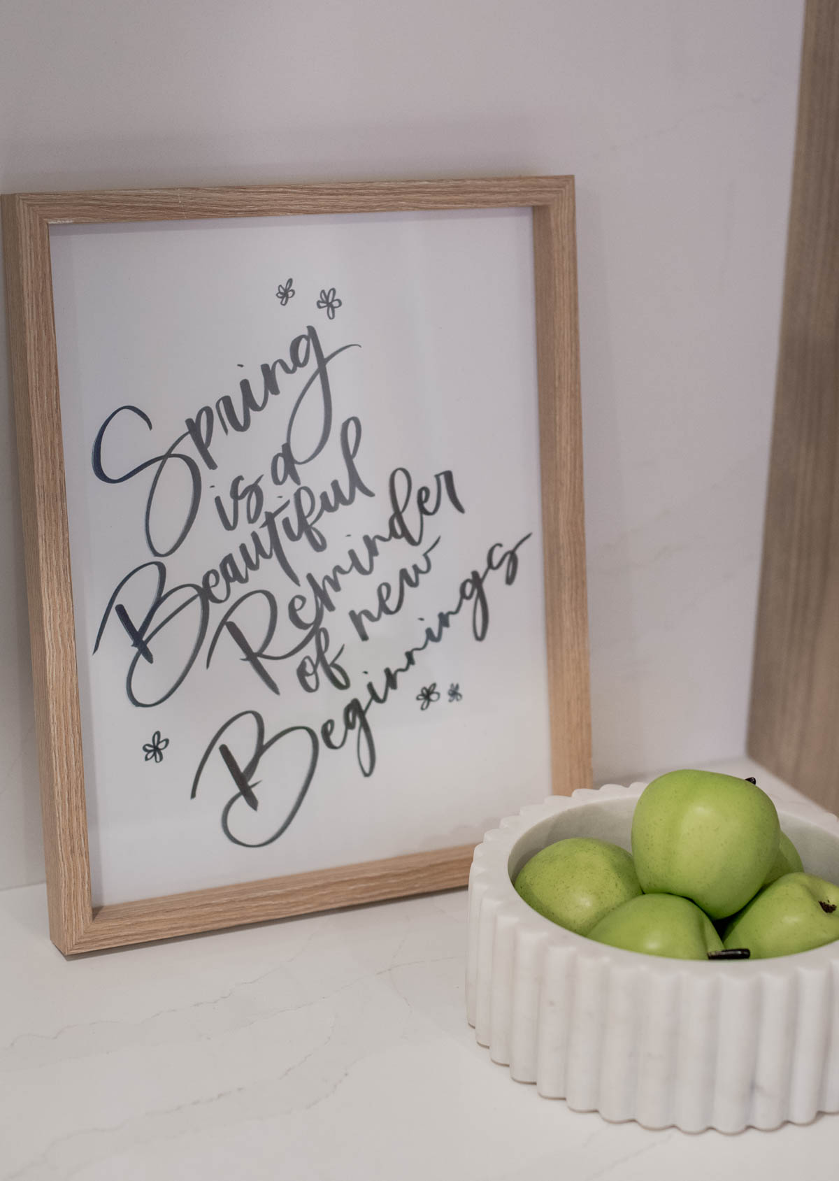 Spring is a beautiful reminder of new beginnings hand lettered art on marble counter styled with marble bowl of apples