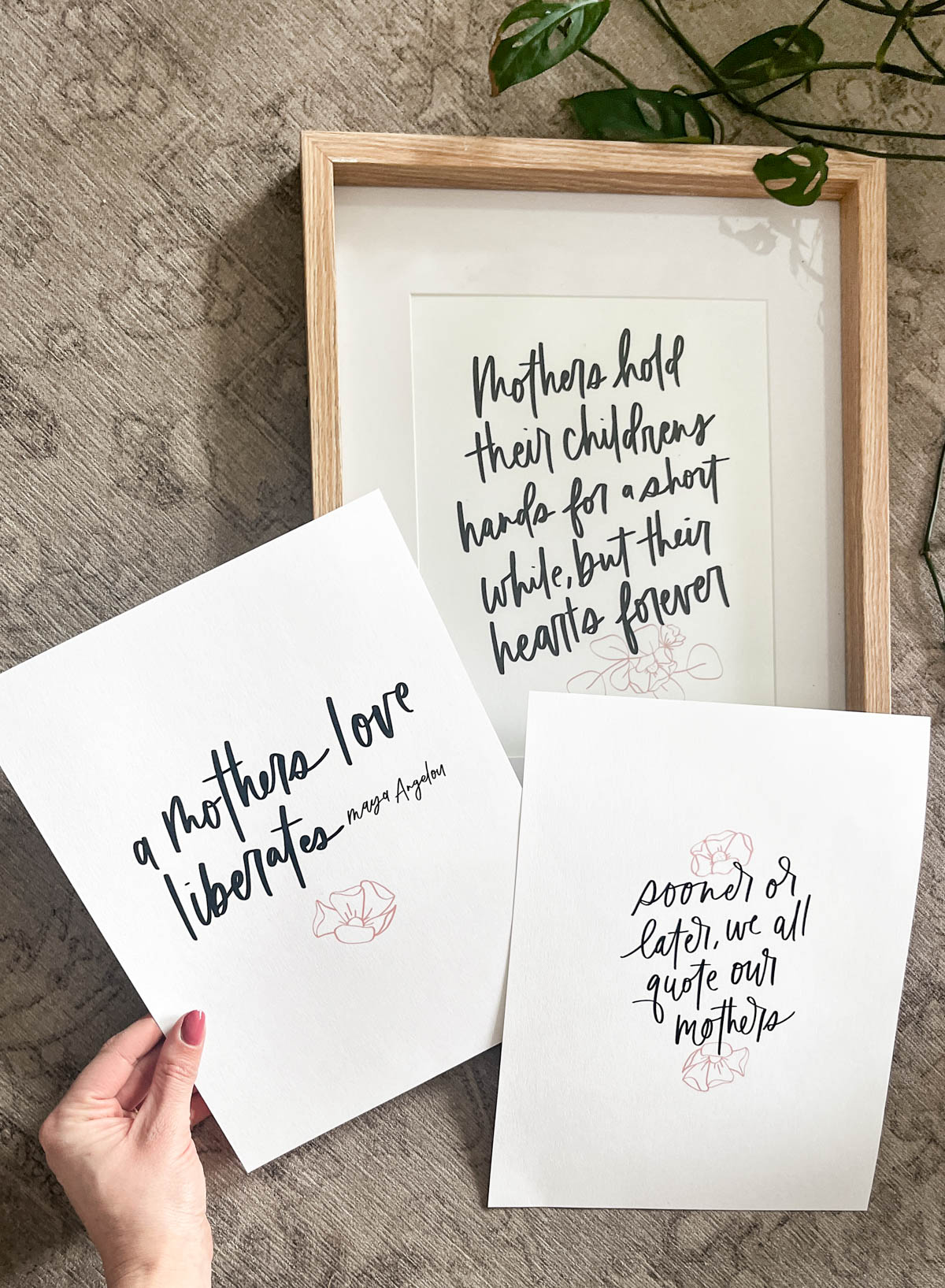 Three free printable quotes for mothers day, printed with one framed. All hand lettered with black writing and a pink accent line floral
