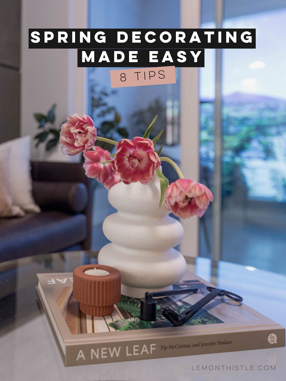 image of tulips in a modern vase on top of a coffee table book with candle. text over reads: spring decorating made easy: 8 tips