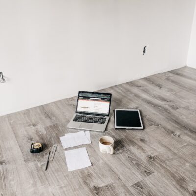 image of computer, measuring tape and papers spread out on floor of unfinished room.