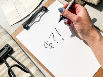 clipboard with dollar signs in sharpie, surrounded by room makeover supplies and samples